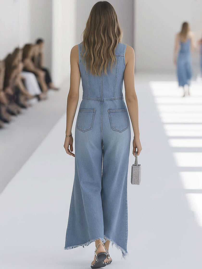 Light blue denim sleeveless jumpsuit by FJØRNA featuring raw edges and wide-leg design, displayed on a hanger.