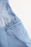 Light blue denim sleeveless jumpsuit by FJØRNA with raw edge details and wide-leg design, displayed on a mannequin.