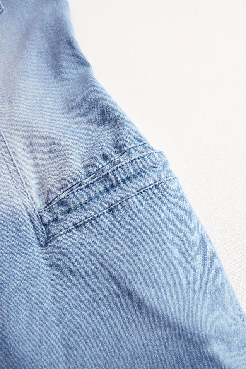 Light blue denim sleeveless jumpsuit by FJØRNA with raw edge details and wide-leg design, displayed on a mannequin.