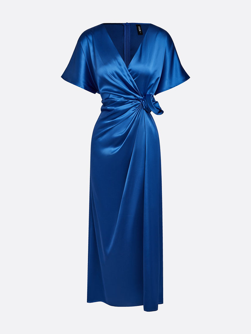 FJØRNA draped maxi dress featuring ruched V-neck and raglan sleeves, flowing fabric, and elegant design.