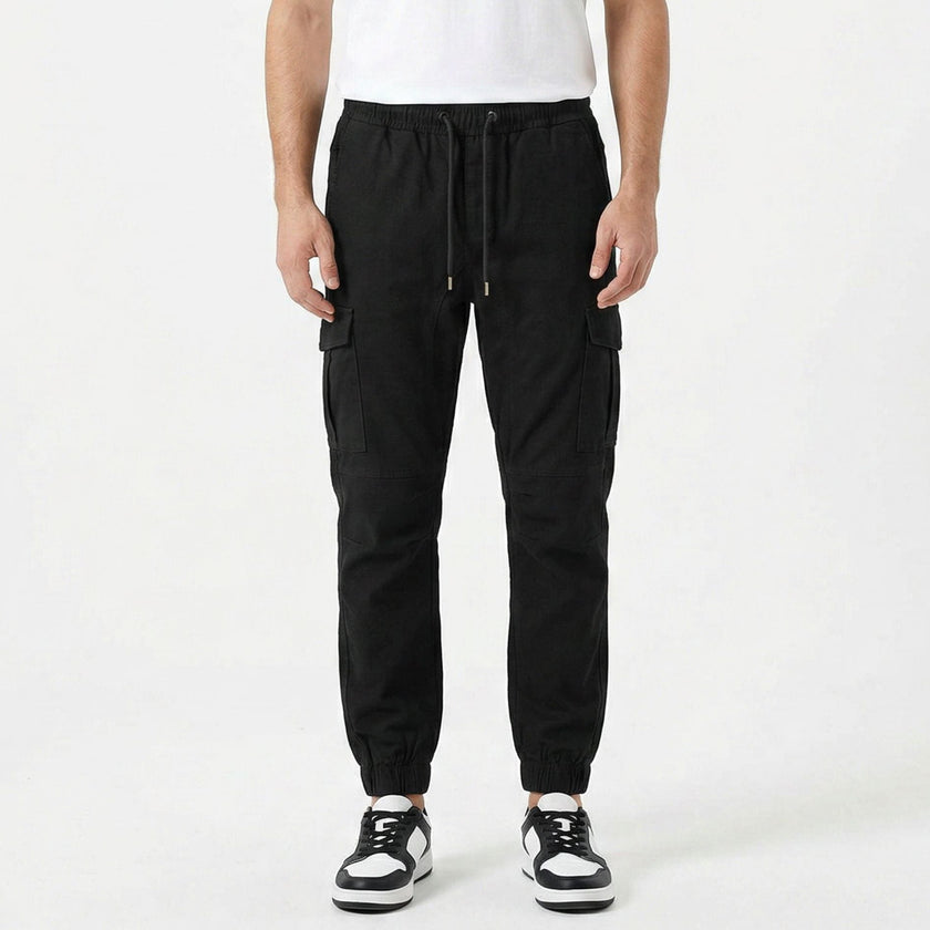 Men's slim fit cotton cargo trousers by FJØRNA, shown in a neutral color, with multiple pockets and a tapered leg fit.