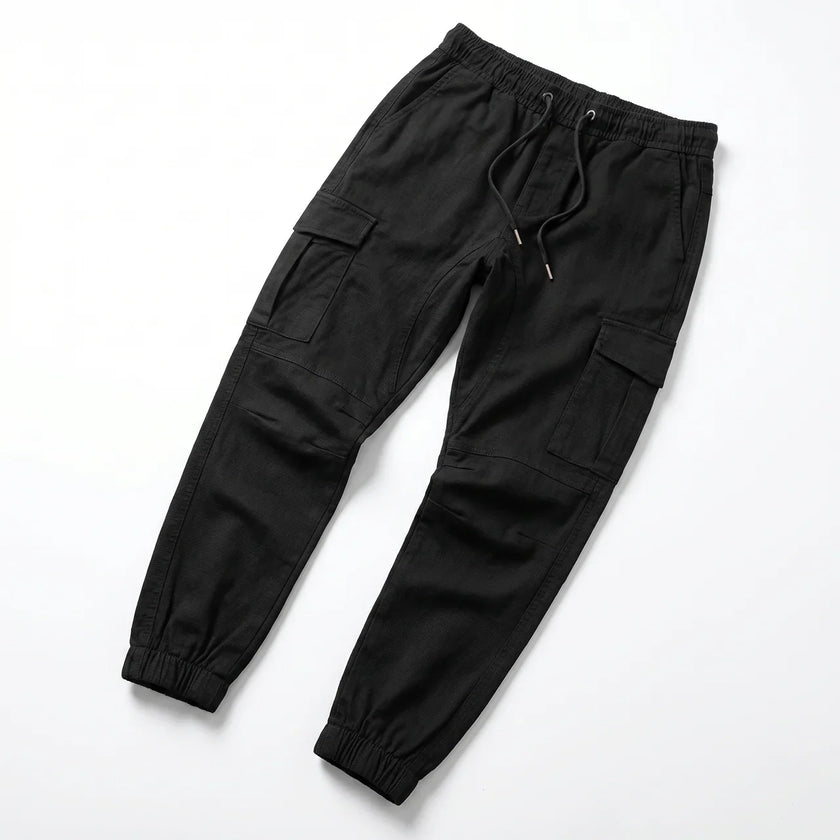 Men's slim fit cotton cargo trousers by FJØRNA, showing the front view with multiple cargo pockets and a tapered leg fit.