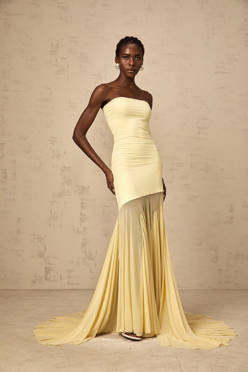 FJØRNA Josiane yellow off-shoulder sheer tulle maxi dress displayed on a hanger, showcasing its flowing fabric and elegant design.
