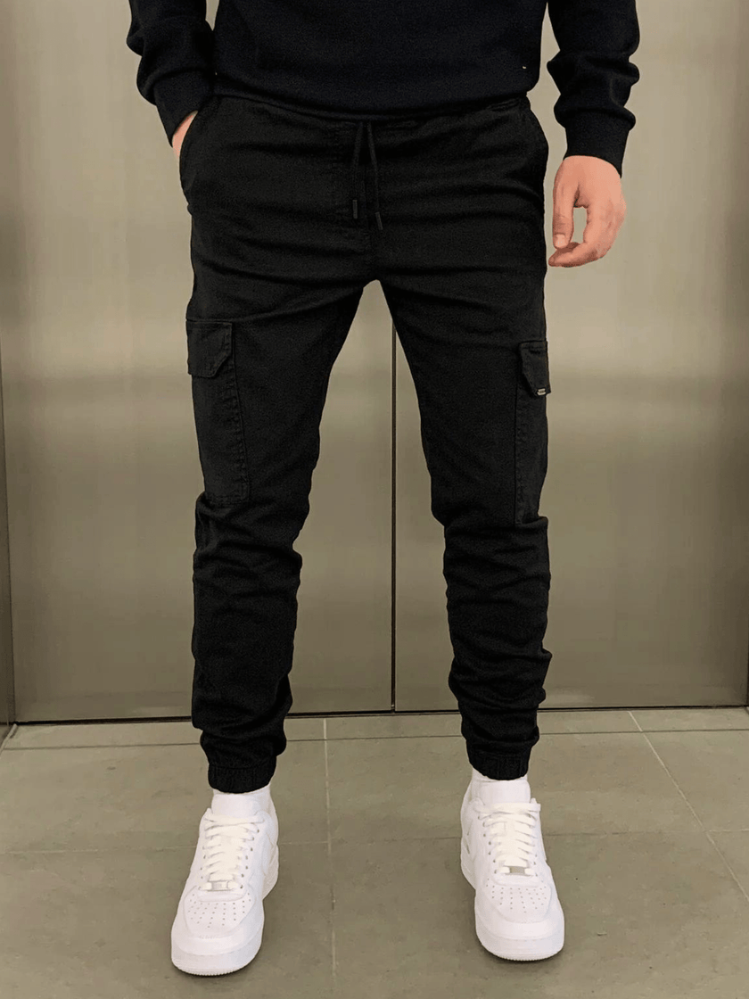 FJØRNA black cargo jogger trousers featuring multiple pockets and a relaxed fit, made from comfortable, durable fabric.