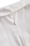 White FJØRNA pleated mini shirt dress with a collared neckline and short sleeves, styled with a flowing, feminine silhouette.