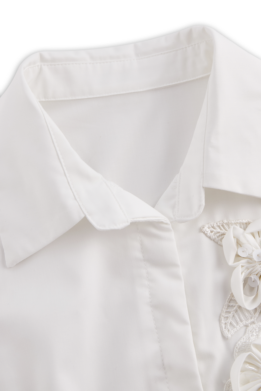 White sleeveless women's blouse from FJØRNA with floral embroidery and 3D appliqué, featuring a stylish and elegant design.