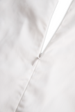 White sleeveless women's blouse with floral embroidery and 3D appliqué, by FJØRNA, showcasing intricate design details.