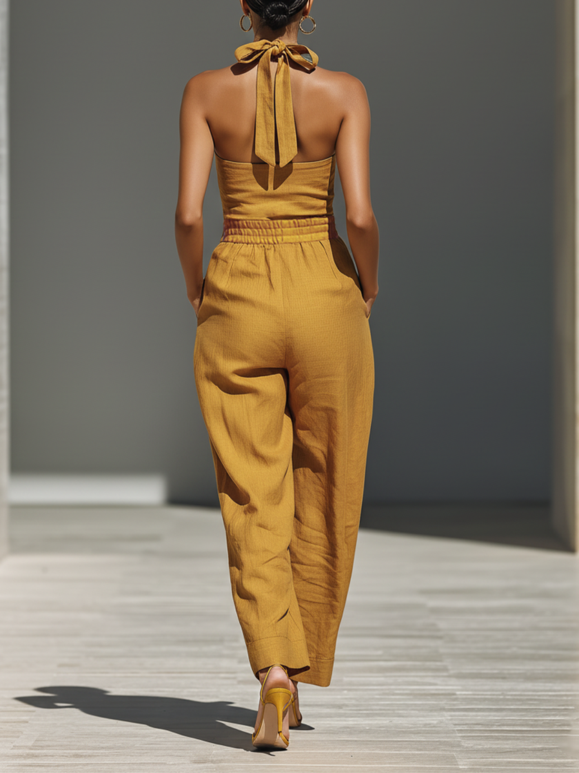 FJØRNA mustard linen-blend women’s jumpsuit with crisscross neckline, relaxed fit, wide-leg style, and comfortable pants.