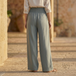 FJØRNA women’s wide leg high waist elastic trousers, featuring relaxed fit and flowing fabric in neutral color.