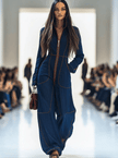 Dark blue FJØRNA denim jumpsuit with wide-leg pants and long sleeves, featuring topstitch details and a relaxed fit.