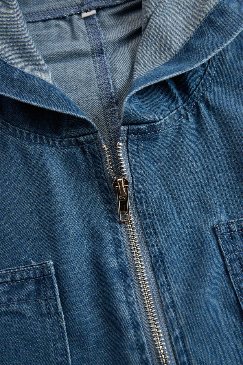 FJØRNA casual loose retro denim jumpsuit with long sleeves, hood, zipper, and front pockets, styled for a relaxed look.