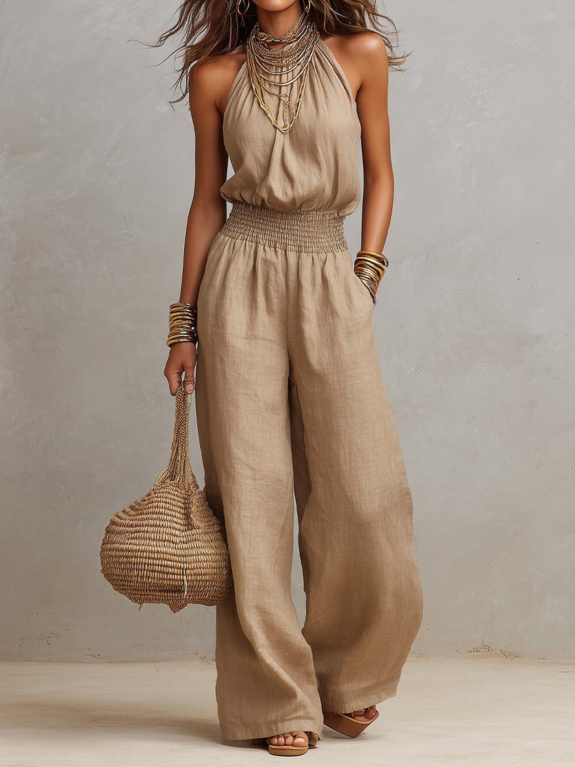 FJØRNA tan cotton linen sleeveless jumpsuit with halter neck, smocked waist, and wide-leg design, perfect for casual summer wear.