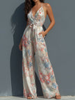 White floral satin halter neck jumpsuit with wrap front and wide-leg design by FJØRNA, shown on a model.