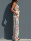 White floral satin jumpsuit by FJØRNA featuring a halter neck, wrap front, and wide-leg trousers.