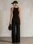 FJØRNA black colour-block V-neck sleeveless button-down jumpsuit displayed on a model, showcasing stylish design and fitted silhouette.