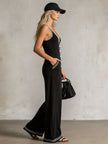 Black colour-block V-neck sleeveless jumpsuit by FJØRNA with button-down front and fitted waist, shown on a model.