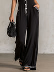 Black colour-block V-neck sleeveless jumpsuit by FJØRNA with button-down front and fitted waist, displayed on a hanger.