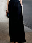 FJØRNA elegant sleeveless maxi dress with draped design and waist definition, perfect for formal occasions.