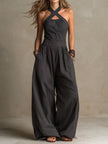FJØRNA charcoal pinstripe halter neck wide-leg jumpsuit styled on a model, featuring a fitted halter top and flowing wide-leg trousers.