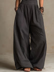 FJØRNA charcoal pinstripe halter neck wide-leg jumpsuit with sleeveless design and relaxed fit on a model.