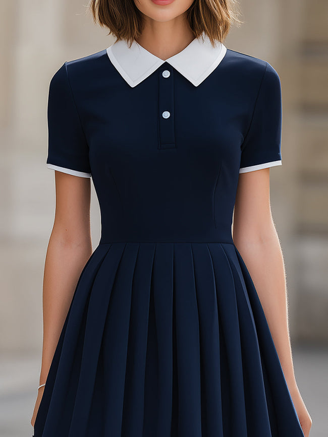 Navy blue contrast collar polo neck pleated flared A-line mini dress by FJØRNA showing front view with pleated skirt and collar detail.