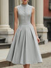 FJØRNA high neck button-front pleated A-line midi dress hanging on a white background, showcasing its elegant design and pleated details.