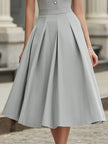 FJØRNA high neck button front pleated A-line midi dress hanging on a mannequin, showcasing its elegant design and pleated fabric.