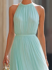FJØRNA halter neck pleated flowing maxi dress in soft fabric, featuring a long, elegant design with a stylish neckline.