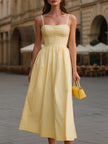 FJØRNA pale yellow spaghetti strap midi dress with ruched bust and flared A-line skirt, perfect for summer occasions.