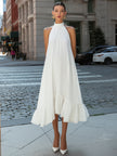 FJØRNA pleated sleeveless halter neck flowing asymmetric midi dress displayed on a model in a sunny outdoor setting.