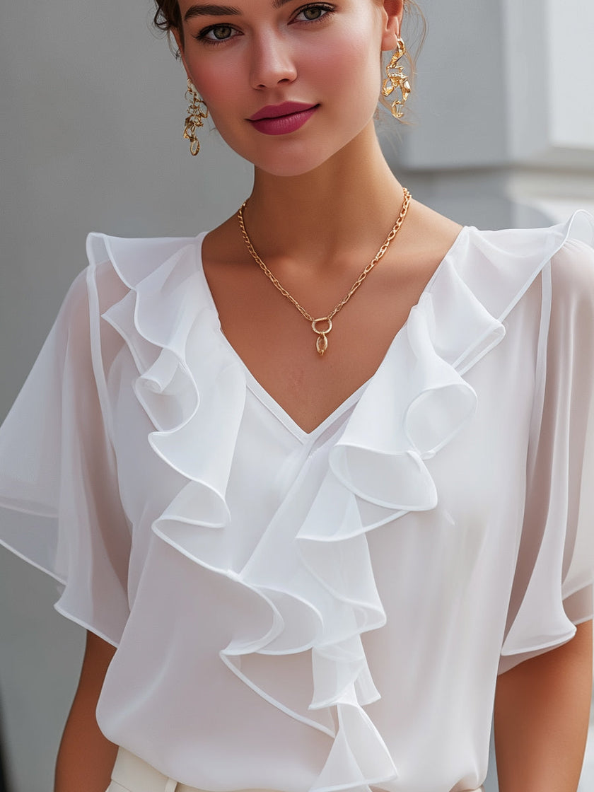 White FJØRNA women's V-neck blouse with sheer sleeves and ruffle details, stylish and elegant top for women.