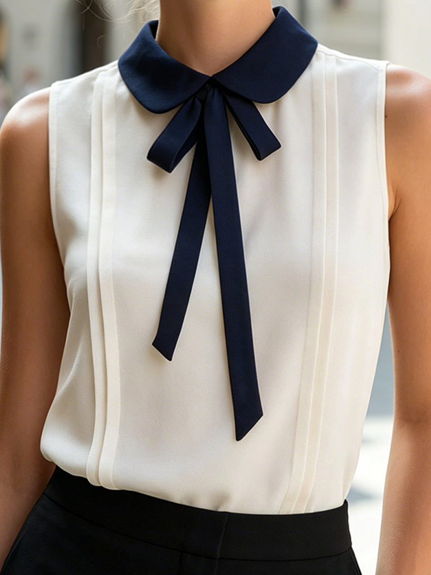 Ivory sleeveless women's blouse by FJØRNA with Peter Pan collar and bow tie, stylish top for casual or formal wear.