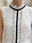 Ivory chiffon sleeveless blouse for women with ruffle high neck and black contrast trim, stylish FJØRNA top.