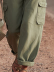 FJØRNA green women's cargo pants with multiple pockets, casual tapered trousers, made from lightweight fabric, front and side view.