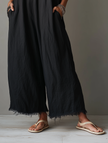 FJØRNA linen-blend women's jumpsuit with spaghetti straps, lace neckline, frayed hem, and loose fit, shown on a model.