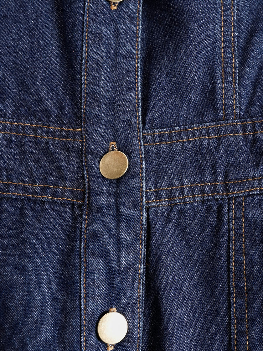 Dark blue denim FJØRNA jumpsuit with multi-pocket design, sleeveless balloon style, featuring a relaxed fit and casual, stylish look.