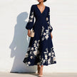 FJØRNA elegant floral print long-sleeved V-neck pleated dress displayed on a hanger, showcasing its flowing fabric and intricate floral pattern.
