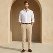 FJØRNA men's linen straight-leg pleated trousers displayed on a hanger, showcasing the light, breathable fabric and tailored fit.