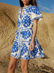FJØRNA women's mini dress with Mediterranean-style printed design, featuring a tie waist and stylish sleeveless cut.