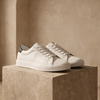 FJØRNA men's leather trainers shoes with sleek design, white soles, and black leather upper on a plain background.