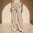 Women’s beige asymmetric waist trousers with metal buckle from FJØRNA, featuring a stylish tailored fit and modern design.