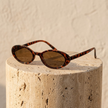 Unisex retro oval sunglasses by FJØRNA with dark tinted lenses and thin frame, stylish accessory for women.