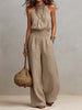 Tan cotton linen sleeveless jumpsuit by FJØRNA with halter neck, smocked waist, and wide-leg design.