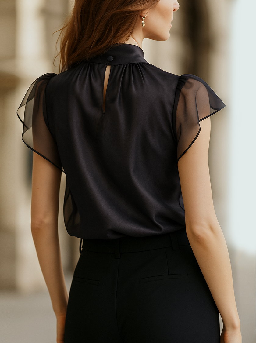 Black chiffon blouse for women by FJØRNA featuring a high neck and sleeveless design, displayed on a model.
