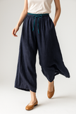 FJØRNA women's tapered linen trousers displayed flat, showcasing the lightweight, elegant fabric and relaxed fit.
