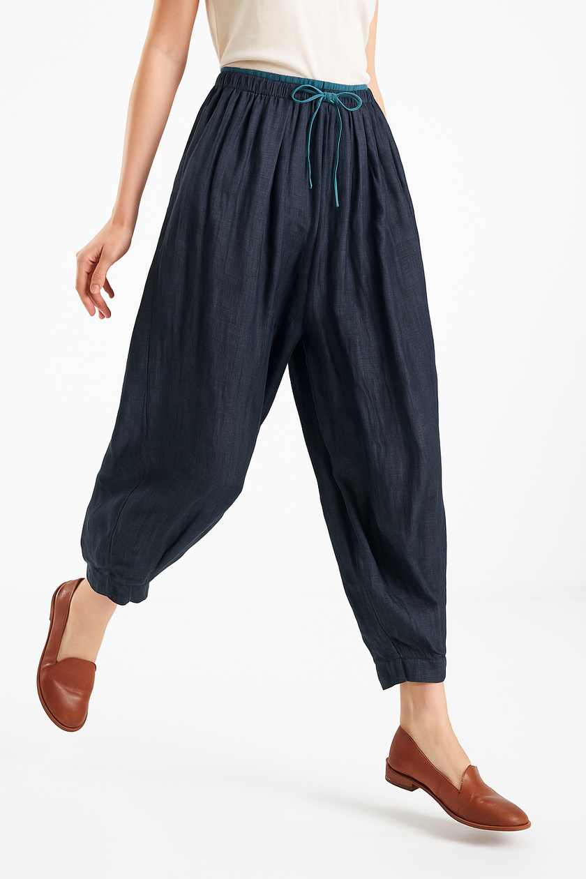 FJØRNA women's linen tapered trousers displayed flat, showcasing light, breathable fabric and modern, elegant design.