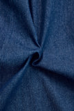 Dark blue FJØRNA denim jumpsuit with wide-leg pants and long sleeves, featuring topstitch detailing on the fabric.