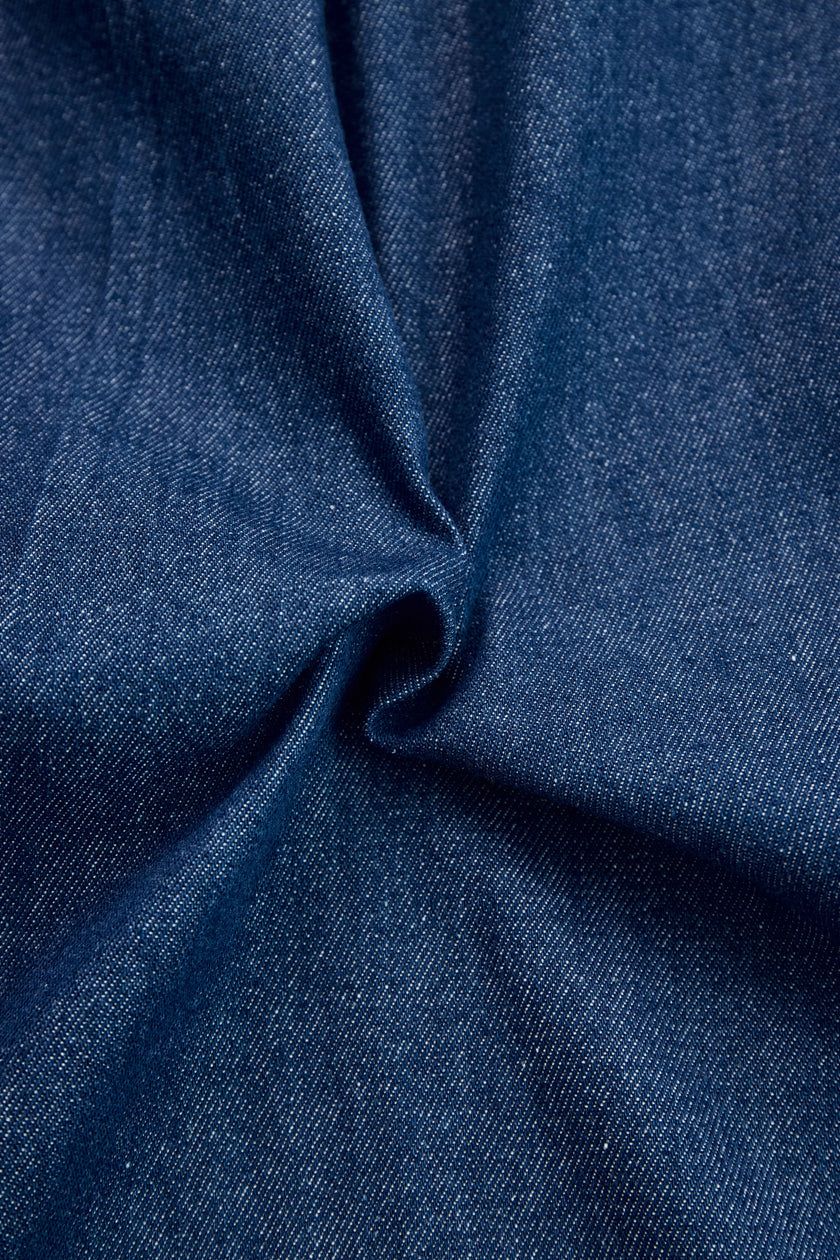 Dark blue FJØRNA denim jumpsuit with wide-leg pants and long sleeves, featuring topstitch detailing on the fabric.