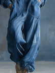 Blue denim hooded jumpsuit with button-front and long sleeves by FJØRNA, shown on a model.