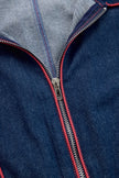 Dark blue FJØRNA denim jumpsuit with topstitching, wide-leg design, and long sleeves, hanging on a hanger against a neutral background.